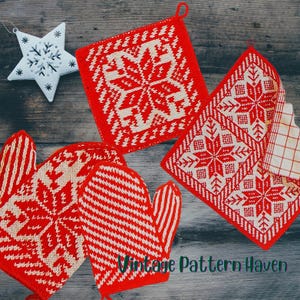 Pode incluir: Uma coleção de itens de cozinha de malha vermelha e branca com padrões de flocos de neve, incluindo luvas de forno, pegadores de panela e um enfeite de estrela. Os itens são dispostos em uma superfície de madeira, criando uma cena aconchegante e festiva.