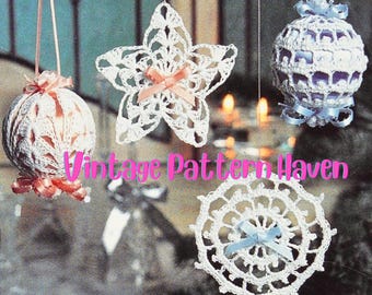 May include: Three crocheted Christmas ornaments: a star, a ball, and a round doily. The star and doily are white, the ball is light pink. Each ornament has a ribbon tied around it.