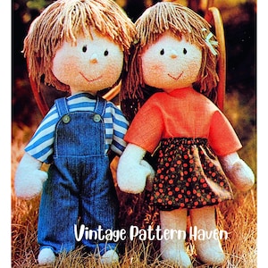 May include: Two handmade rag dolls. One doll wears blue denim overalls over a blue and white striped shirt. The other doll wears an orange top and a black skirt with a red floral pattern. The dolls have yarn hair and stitched facial features. The text "Vintage Pattern Haven" is at the bottom.