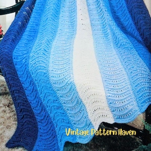May include: A crocheted blanket in shades of blue and white, with a wave-like pattern. The blanket transitions from dark blue to light blue and white. The text "Vintage Pattern Haven" is visible in the lower right corner.