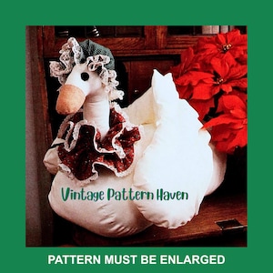 May include: A white goose-shaped decorative item with a green and white bonnet, a red and white ruffled collar, and a brown beak. The text "Vintage Pattern Haven" is visible. The phrase "PATTERN MUST BE ENLARGED" is also visible.