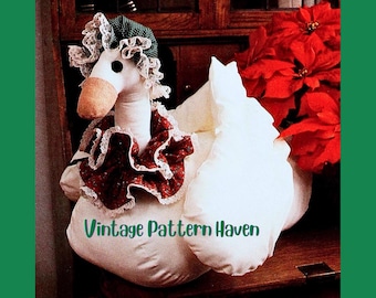 May include: A white goose-shaped decorative item with a green and white bonnet, a red and white ruffled collar, and a brown beak. The text "Vintage Pattern Haven" is visible. The phrase "PATTERN MUST BE ENLARGED" is also visible.