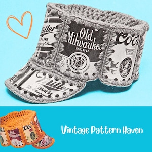 Pode incluir: Uma viseira feita à mão, de crochê com rótulos de latas de cerveja. A viseira incorpora rótulos de Miller, Old Milwaukee e Coors. O design inclui uma aba de crochê cinza e um fundo azul. O texto "Vintage Pattern Haven" também é visível.