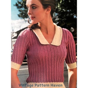 May include: A pink knitted sweater with a white collar and short sleeves. The sweater has a delicate openwork pattern.