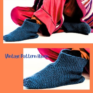May include: A pair of dark blue knitted slipper socks. The socks are thick and textured, with a ribbed cuff and a rounded toe. The image also includes the text "Vintage Pattern Haven".