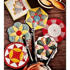 May include: A set of six colorful quilted hot pads with various geometric patterns. The hot pads are made of fabric and have a quilted design. They are arranged on a wooden surface with a copper pot and a wooden spoon.