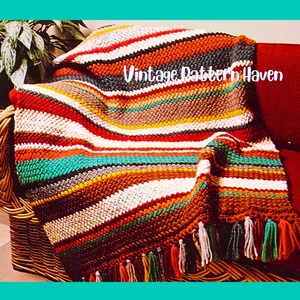 May include: A colorful, striped crochet blanket with a fringe. The blanket features a variety of colors, including red, orange, white, green, and brown. The text "Vintage Pattern Haven" is visible on the blanket.