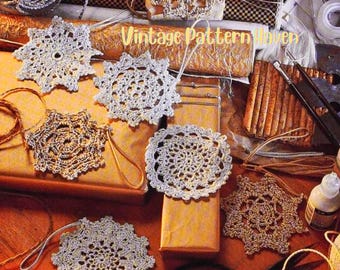 May include: A collection of handmade crochet ornaments in various shapes and colors, including snowflakes and circular doilies. The ornaments are in shades of silver, gold, and cream, with a vintage aesthetic. The text "Vintage Pattern Haven" is visible.