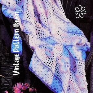 Peut inclure: Une couverture au crochet dans les tons de blanc, bleu et rose, drapée sur une surface sombre. La couverture présente un motif ajouré avec des motifs complexes et le texte "Vintage Pattern Haven" en blanc.