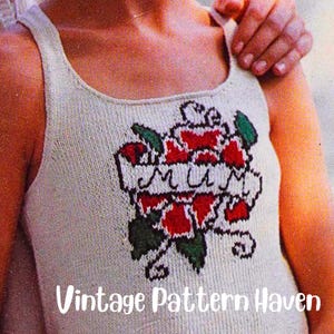 Op de afbeelding: Een wit gebreid tanktop met een rode roos en het woord "Mummy" geborduurd op de voorkant. Het tanktop is een vintage patroon.