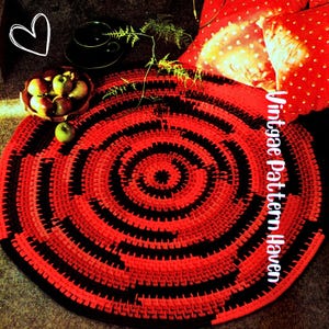 Puede incluir: Una alfombra redonda tejida en rojo y negro con un diseño de espiral concéntrica. La alfombra está rodeada de cojines rojos con lunares blancos, un cuenco de manzanas y una taza y platillo. El texto "Vintgae Pattern Haven" está en el lado derecho.