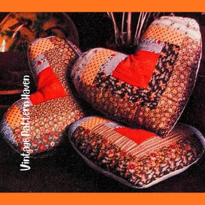 Puede incluir: Tres cojines en forma de corazón con diseños de patchwork. Los cojines presentan una variedad de telas en tonos rojos, marrones y crema. El texto "Vintage Pattern Haven" es visible en el lado izquierdo de la imagen.