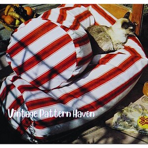 Könnte beinhalten: Ein gestreifter rot-weißer Outdoor-Loungesessel mit passendem rundem Kissen. Eine Siamkatze ruht auf dem Stuhl. Der Text "Vintage Pattern Haven" ist unten im Bild zu sehen.