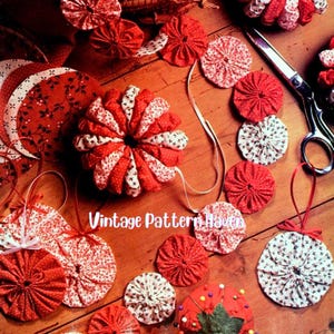 May include: A selection of red and white fabric ornaments and sewing tools on a wooden surface. The ornaments feature round, flower-shaped, and half-moon designs. The text "Vintage Pattern Haven" is visible.