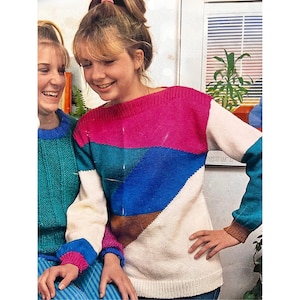 Könnte beinhalten: Ein weißer, rosa, blauer und brauner Strickpullover mit geometrischem Muster. Der Pullover hat einen Bootsausschnitt und lange Ärmel.