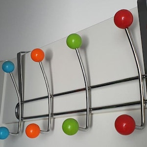Puede incluir: Un perchero multicolor para colgar sobre la puerta con seis ganchos de metal curvados. Cada gancho tiene una bola de colores brillantes en el extremo: azul, naranja, verde y rojo. El perchero está hecho de metal cromado y está diseñado para colgar sobre una puerta.