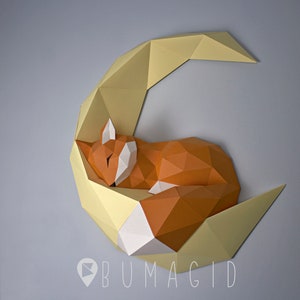 Pu&ograve; includere: Una scultura di carta di una volpe che dorme su una luna crescente. La volpe &egrave; arancione e bianca, e la luna &egrave; gialla. La scultura &egrave; realizzata in carta piegata ed &egrave; un design 3D.
