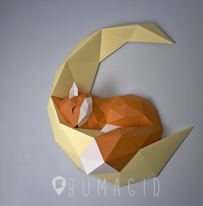 Pu&ograve; includere: Una scultura di carta di una volpe che dorme su una luna crescente. La volpe &egrave; arancione e bianca, e la luna &egrave; gialla. La scultura &egrave; realizzata in carta piegata ed &egrave; un design 3D.