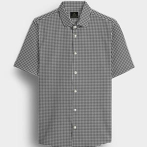 Pode incluir: Uma camisa de manga curta com um padr&atilde;o de pata de galo a preto e branco. A camisa tem uma gola cl&aacute;ssica e uma s&eacute;rie de bot&otilde;es brancos na frente. O tecido parece ser um material leve.