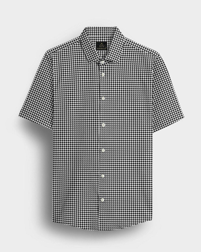 Pode incluir: Uma camisa de manga curta com um padr&atilde;o de pata de galo a preto e branco. A camisa tem uma gola cl&aacute;ssica e uma s&eacute;rie de bot&otilde;es brancos na frente. O tecido parece ser um material leve.