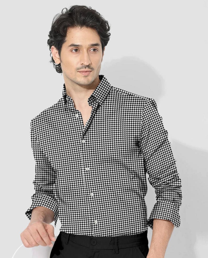 Pode incluir: Uma camisa abotoada com padr&atilde;o pied-de-poule em preto e branco. A camisa de manga comprida tem uma gola cl&aacute;ssica e &eacute; abotoada na frente. A camisa &eacute; combinada com cal&ccedil;as pretas.
