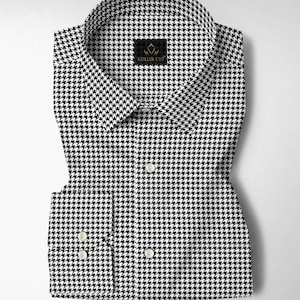 Pode incluir: Uma camisa dobrada com estampa pied-de-poule em preto e branco. A camisa tem uma gola cl&aacute;ssica e punhos abotoados. A marca "KOLLER CUT" &eacute; exibida em uma pequena etiqueta preta perto da gola.