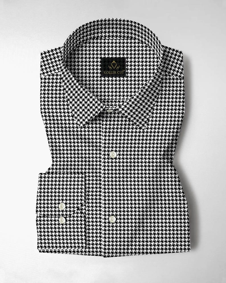 Pode incluir: Uma camisa dobrada com estampa pied-de-poule em preto e branco. A camisa tem uma gola cl&aacute;ssica e punhos abotoados. A marca "KOLLER CUT" &eacute; exibida em uma pequena etiqueta preta perto da gola.