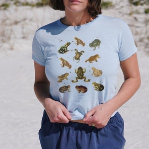 Vintage Frog and Toad graphic Shirt: twelve vintage illustration of frogs and toads decorated with flys printed on a gildan 5000b youth shirt. Here wear by a woman as a trendy 90s baby tee.