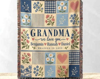 May include: A woven throw blanket featuring a patchwork design of blue and cream squares with floral patterns, gingham checks, and stripes. The centre text reads GRANDMA we love you Benjamin Hannah Daniel WRAPPED IN LOVE with heart icons.
