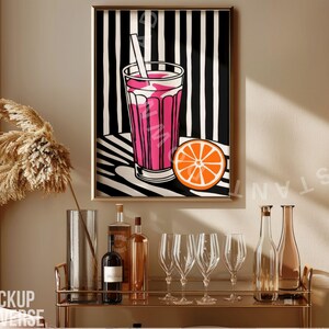 May include: A framed print of a pink drink with a straw and a slice of orange on a black and white striped background. The print is hanging on a wall above a bar cart with bottles and glasses.