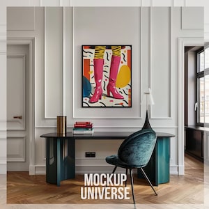 Pode incluir: Um pôster emoldurado em preto com um design abstrato colorido apresentando botas rosa, círculos amarelos e linhas pretas e brancas. O pôster está pendurado em uma parede branca acima de uma mesa preta com uma base verde-azulada. Uma cadeira de veludo verde-azulada com pernas pretas fica na frente da mesa. O texto "MOCKUP UNIVERSE" está impresso no chão na frente da mesa.