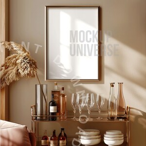May include: A gold metal bar cart with a gold frame mirror above it. The cart is filled with bottles of liquor and glasses. There is a large, dried pampas grass plant in a clear glass vase on the left side of the image.