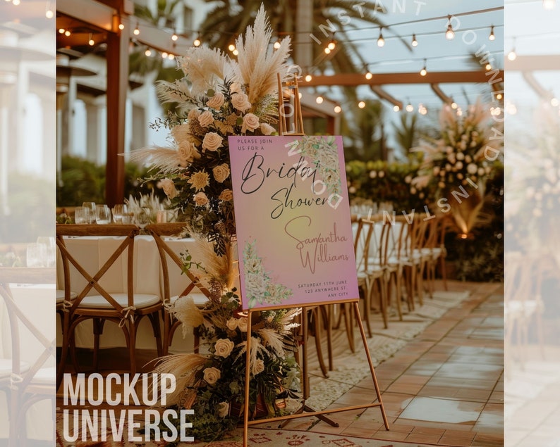 May include: A pink and white bridal shower sign with a floral design and the text "Please join us for a Bridal Shower Samantha Williams Saturday 11th June 123 Somewhere City". The sign is on a gold easel in front of a table with chairs and a floral arrangement.