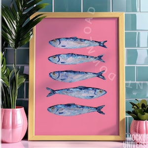 May include: A framed art print featuring five blue and white fish arranged vertically on a pink background. The artwork is set in a gold frame and is displayed against a backdrop of teal tiles. Decorative plants in pink pots are in the foreground.