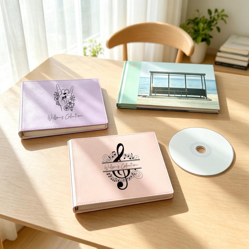 May include: A light purple photo album with a hand gesture and floral graphic, a light pink photo album with a treble clef and musical notes, a photo album with a beach bus stop image, and a blank silver CD, all featuring the text Willson's Collection.
