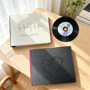 May include: A white square photo album with a black heartbeat line, heart, and the text "music" and "Willson's Collection" on the cover, a black square photo album with a heart made of musical notes, and a black circular compact disc.