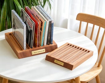 May include: Two rectangular wooden storage racks for compact discs, each featuring multiple parallel grooves for upright display. A small brass-colored metal plate is attached to the front of each rack, engraved with the text "Anna's Collection".