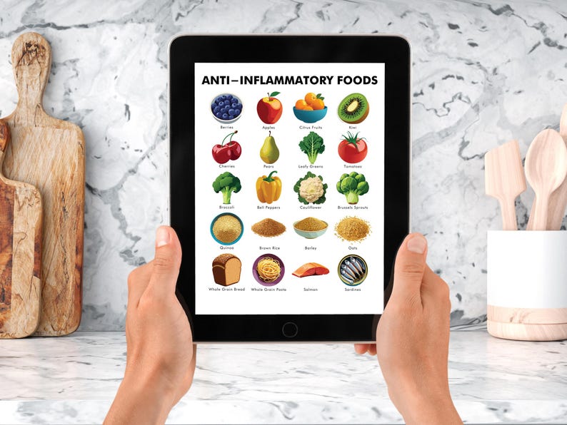 May include: A tablet displays a colorful infographic titled "ANTI-INFLAMMATORY FOODS." The image showcases various fruits, vegetables, grains, and fish, including berries, apples, kiwi, tomatoes, and salmon. The tablet is held in front of a marble countertop.