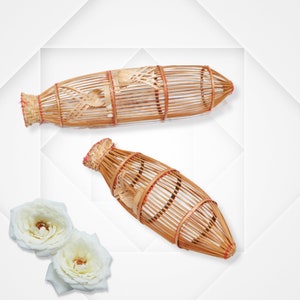 Könnte beinhalten: Zwei braune geflochtene Bambuskörbe mit roten Akzenten. Der größere Korb ist zylindrisch und der kleinere Korb ist oval.