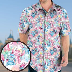 Op de afbeelding: Korte mouwen button-down shirt met een kleurrijk patroon van blauwe en roze cartoonfiguren op een witte achtergrond. Het ontwerp bevat spetters in aquarel-stijl. Het shirt heeft een klassieke kraag en een knoopsluiting.