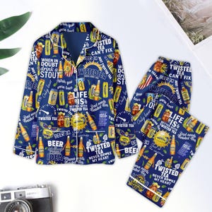 May include: Blue and yellow pajama set with a repeated pattern of Twisted Tea cans and slogans. The top has a button-up closure and long sleeves. The pants have an elastic waistband. The text on the pajamas includes "Twisted Tea", "Beer 30", "Life is better with Twisted Tea", "Dad needs Twisted Tea", "Twisted Tea never broke my heart", and "Beer always the answer".
