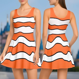 Può includere: Abito senza maniche arancione e bianco con un motivo a righe ondulate e contorni neri, ispirato a un pesce pagliaccio. Presenta uno scollo tondo e una gonna svasata.