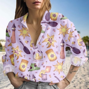 May include: A lilac button-down shirt with a repeating pattern of cartoon suns, lanterns, flowers, and a frying pan. The shirt also features the text "The Snuggly Duckling".