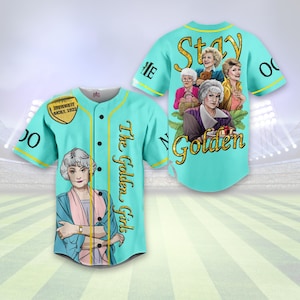 May include: A turquoise baseball jersey with the text "Stay Golden" and images of the Golden Girls on the back. The front of the jersey has the text "The Golden Girls" and an image of one of the Golden Girls.