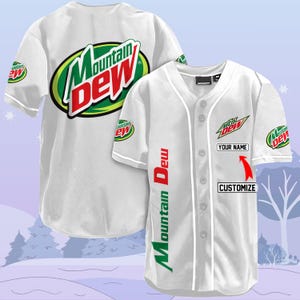Puede incluir: Jersey de béisbol blanco con un logotipo de Mountain Dew verde y blanco en la parte delantera y las mangas. El jersey tiene un cuello y mangas blancas con una franja blanca en el lateral. El texto "Mountain Dew" está impreso verticalmente en el lado derecho del jersey. El texto "Your Name" está impreso en un rectángulo blanco en la parte delantera del jersey. El texto "Customize" está impreso debajo del rectángulo.