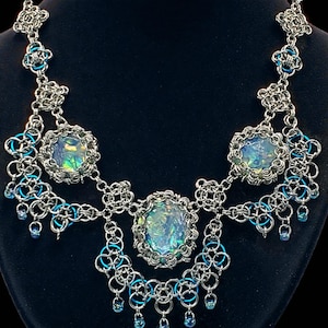 Op de afbeelding: Een handgemaakt houten bord met de tekst "Welkom in ons huis" in een handgeschreven stijl. Het bord is wit geschilderd met een verweerde afwerking en heeft een decoratief bloemmotief in de hoek.