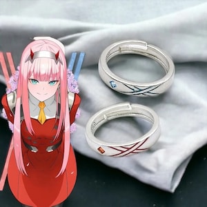 Puede incluir: Dos anillos de plata con piedras preciosas rojas y azules. Los anillos tienen un diseño de cruz.