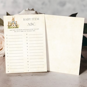 May include: A printable baby shower game card with a list of letters from A to Z. The game instructions are "What baby item begins with each letter the host will set a timer. Get the most win!"  The card features a cartoon illustration of a rabbit sitting on a bench.