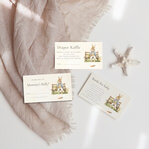 Puede incluir: Tres tarjetas con un tema de Peter Rabbit para un baby shower. Las tarjetas son blancas con un fondo marr&oacute;n claro y presentan una ilustraci&oacute;n de Peter Rabbit. El texto en las tarjetas dice "Rifa de pa&ntilde;ales", "&iquest;Qu&eacute; tan grande est&aacute; la barriga de mam&aacute;?" y "Libros para el beb&eacute;".