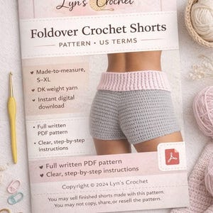 以下が含まれることがあります： Lyn's CrochetのFoldover Crochet Shortsのパターン。グレーのクロシェ編みショートパンツとピンクのウエストバンドが写っています。パターンはS-XLサイズで、DKウェイトの糸を使用しています。かぎ針、糸、ハサミも写っています。